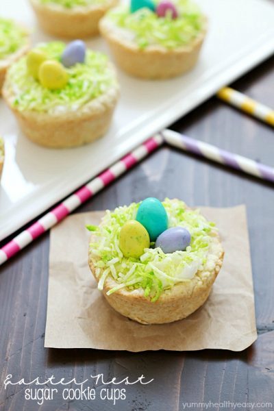 Need a fun treat to make for an Easter get together? Make these darling Easter Nest Sugar Cookie Cups! Sugar cookie dough cooked in a muffin tin, filled with vanilla frosting, topped with green tinted coconut and M&M eggs to look like a little bird's nest. So cute and great for spring! #truvia
