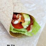 Bacon, Lettuce, Tomato & Avocado wrap on some parchment paper.