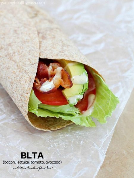 Bacon, Lettuce, Tomato & Avocado wrap on some parchment paper.
