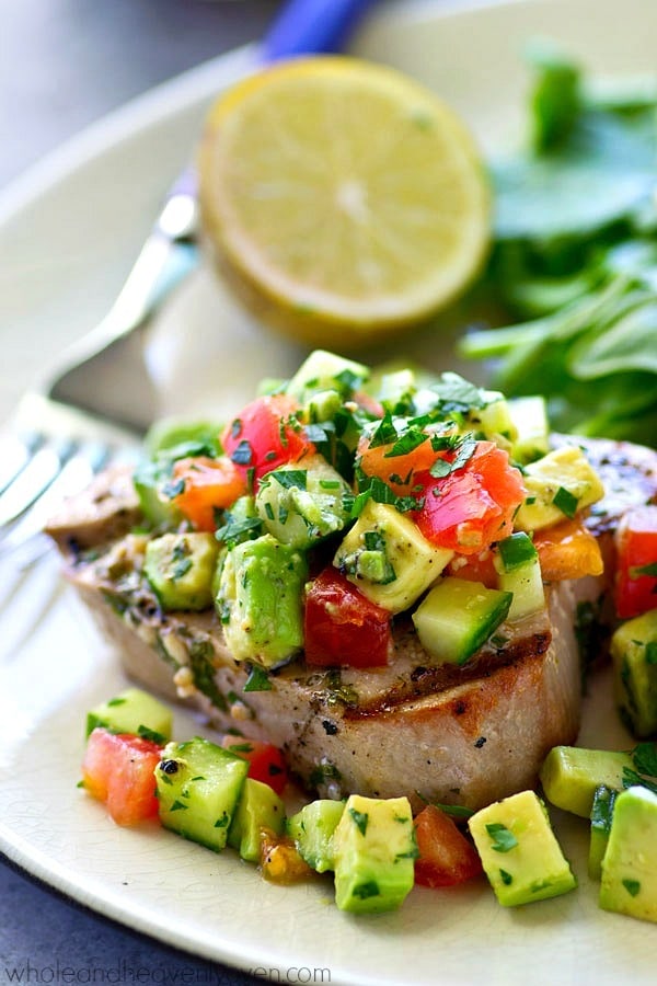 Tender tuna steaks are marinated in cilantro and lots of lime, grilled until perfectly smoky, and topped with an amazing fresh avocado cucumber salsa for one easy summer dinner!