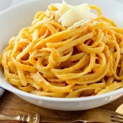 Creamy Pumpkin Pasta in a white bowl and topped with parmesan cheese.