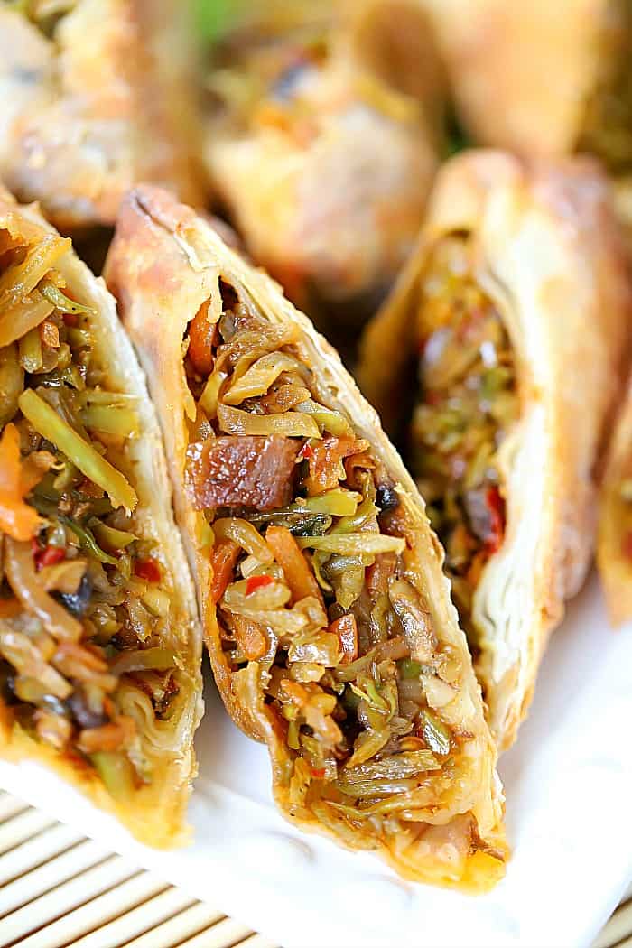 Close up view of the inside of a sliced in half egg roll showing cooked vegetables.