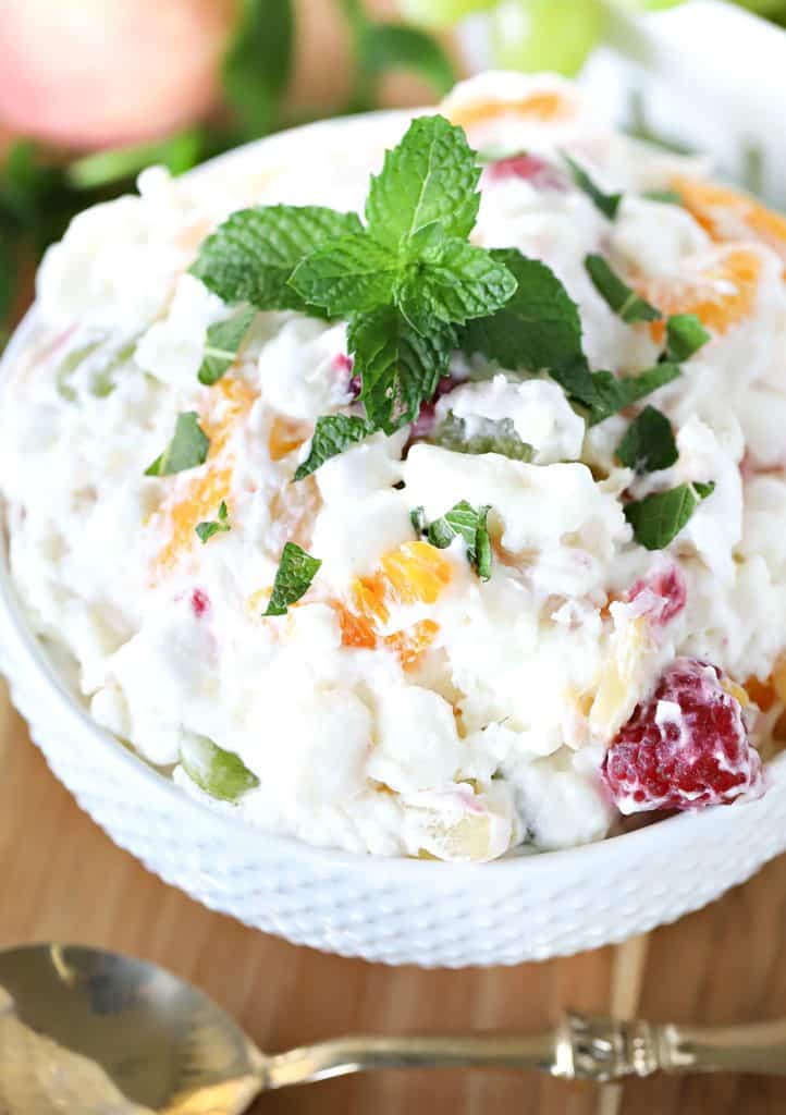 Bowl filled with fruit salad and a mint sprig on top.