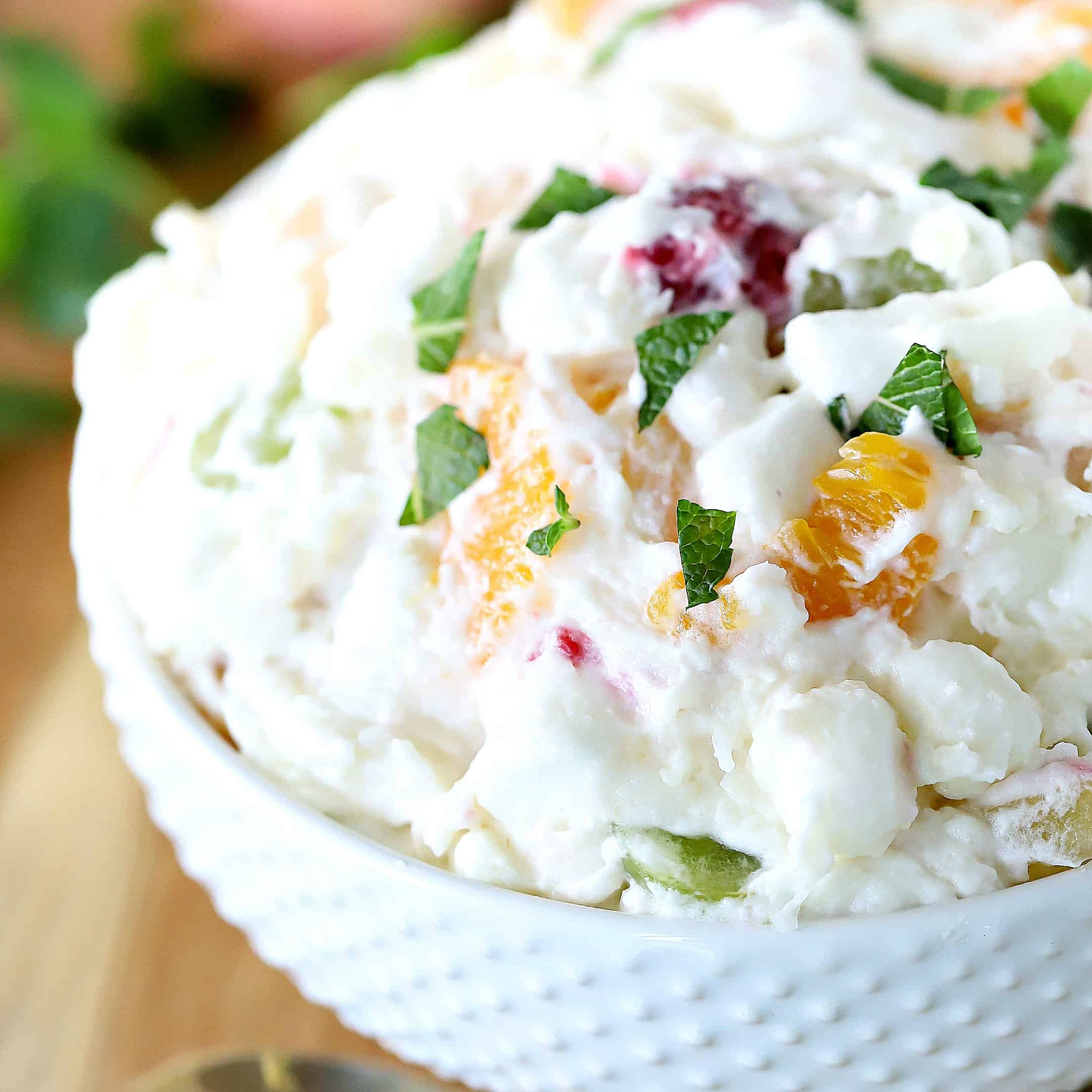 Square image - White bowl filled with fruit salad.
