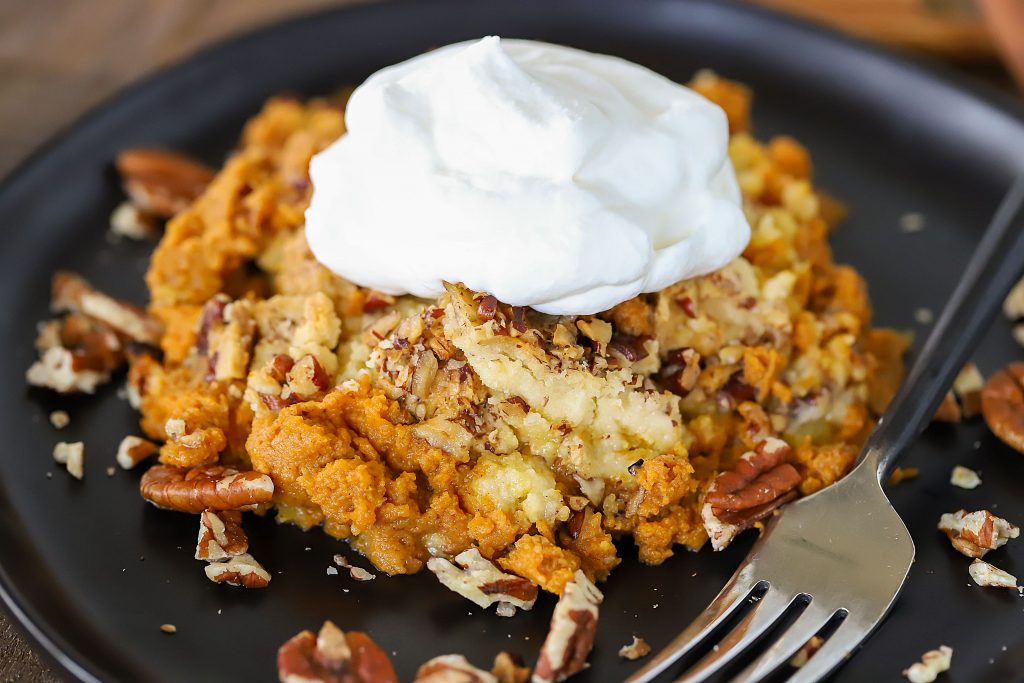 Close up of cake on a plate topped with whipped cream.