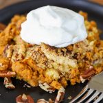 Close up of cake on a plate topped with whipped cream.