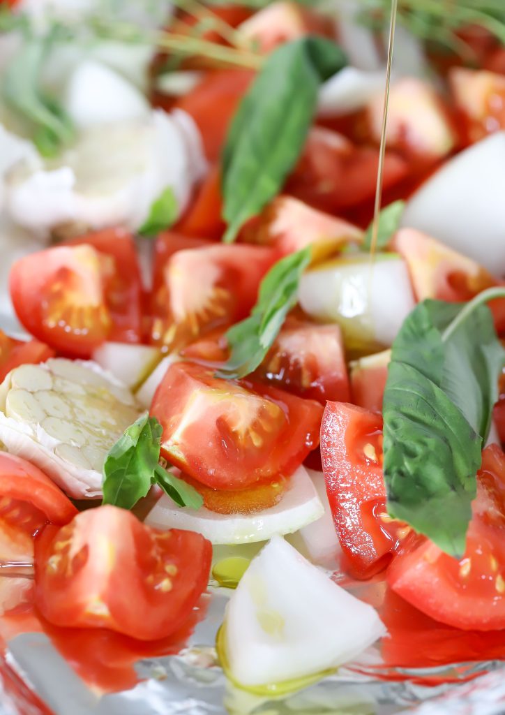 Sheet pan with chopped tomatoes, chopped red bell peppers, garlic and onion.