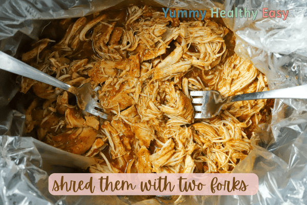 Crock Pot filled with shredded boneless skinless chicken breasts.